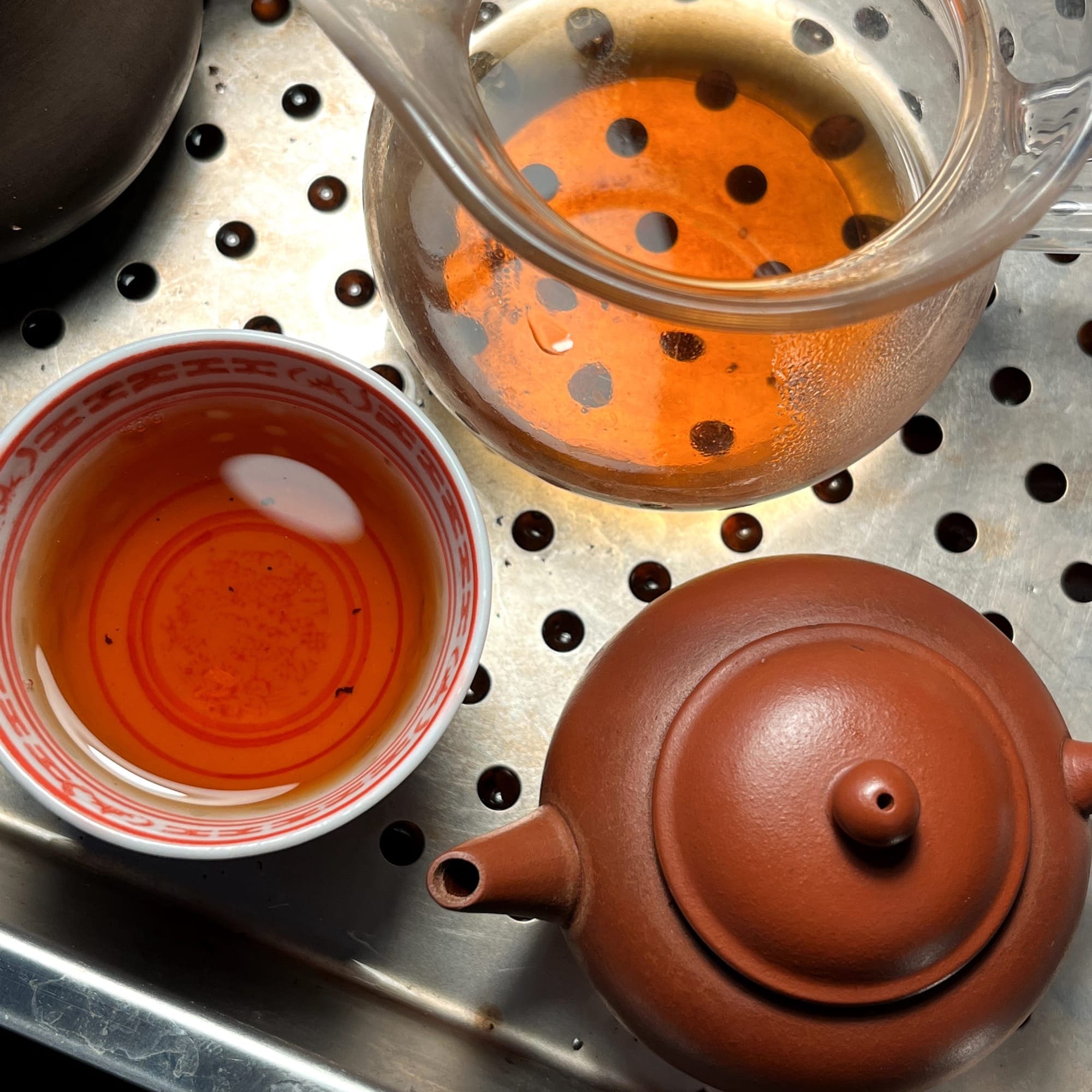 A chinese 1960 hongni teapot and a cup of 98/2004 nanqiao tea beside it